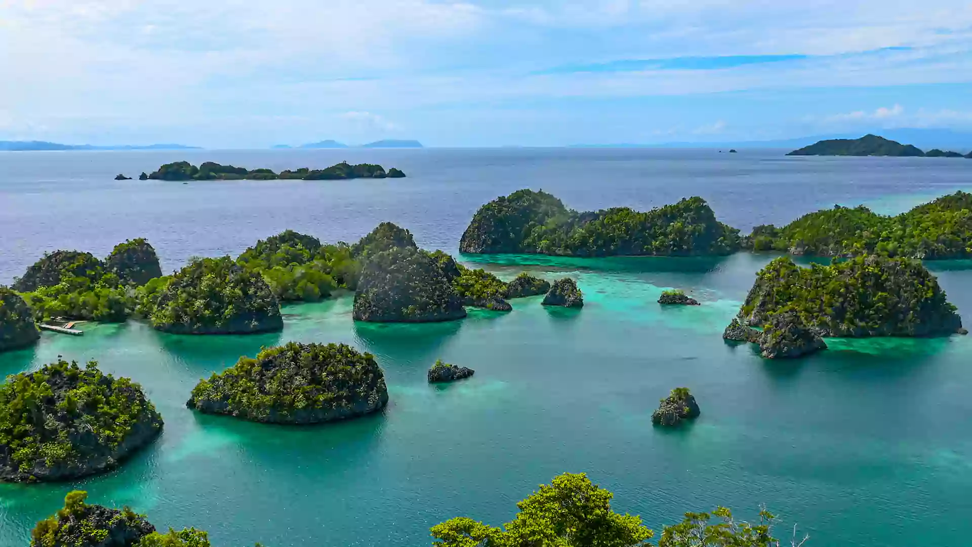 Panorama gugusan pulau kecil di Piaynemo dengan gradasi laut toska dan biru muda yang memukau.