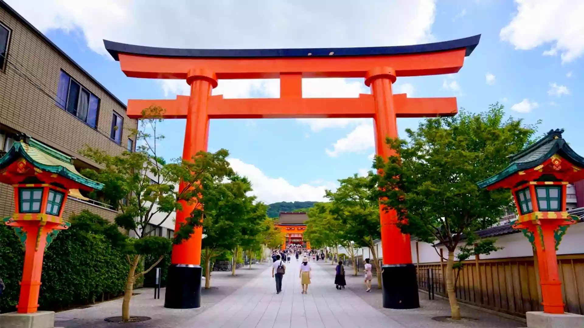 Gerbang torii merah ikonik di Fushimi Inari Taisha Kyoto Jepang dengan suasana tenang dan wisatawan berjalan di jalan menuju kuil.