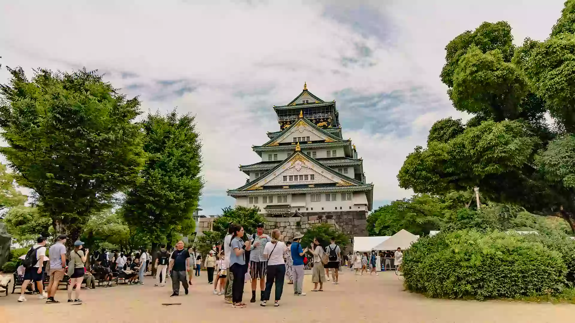 Osaka Castle megah di Jepang dengan pepohonan hijau dan wisatawan yang menikmati suasana bersejarah