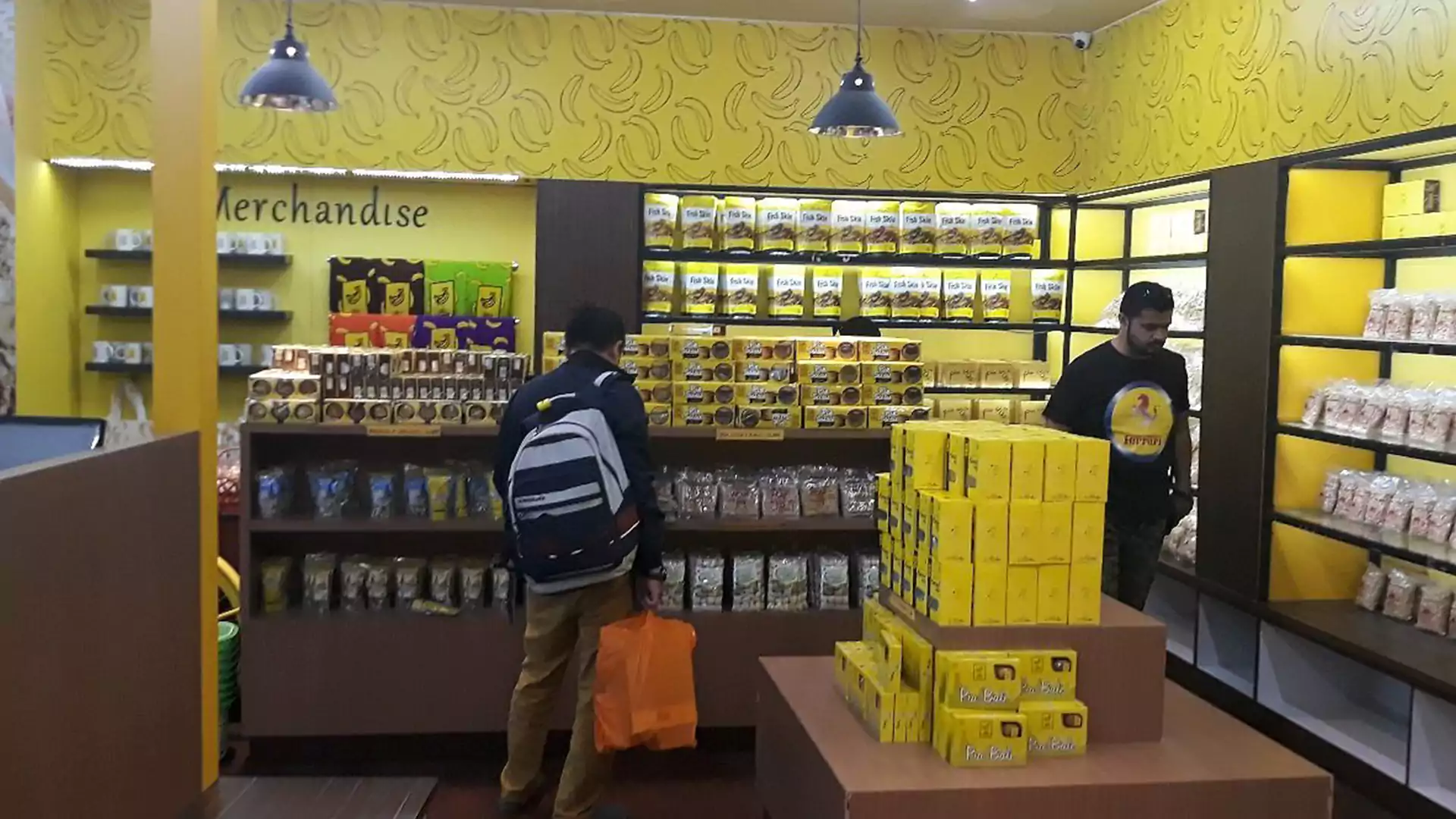 Interior toko Bali Banana dengan deretan camilan kekinian khas Bali berwarna kuning cerah, populer sebagai pusat oleh-oleh Bali modern untuk wisatawan muda.