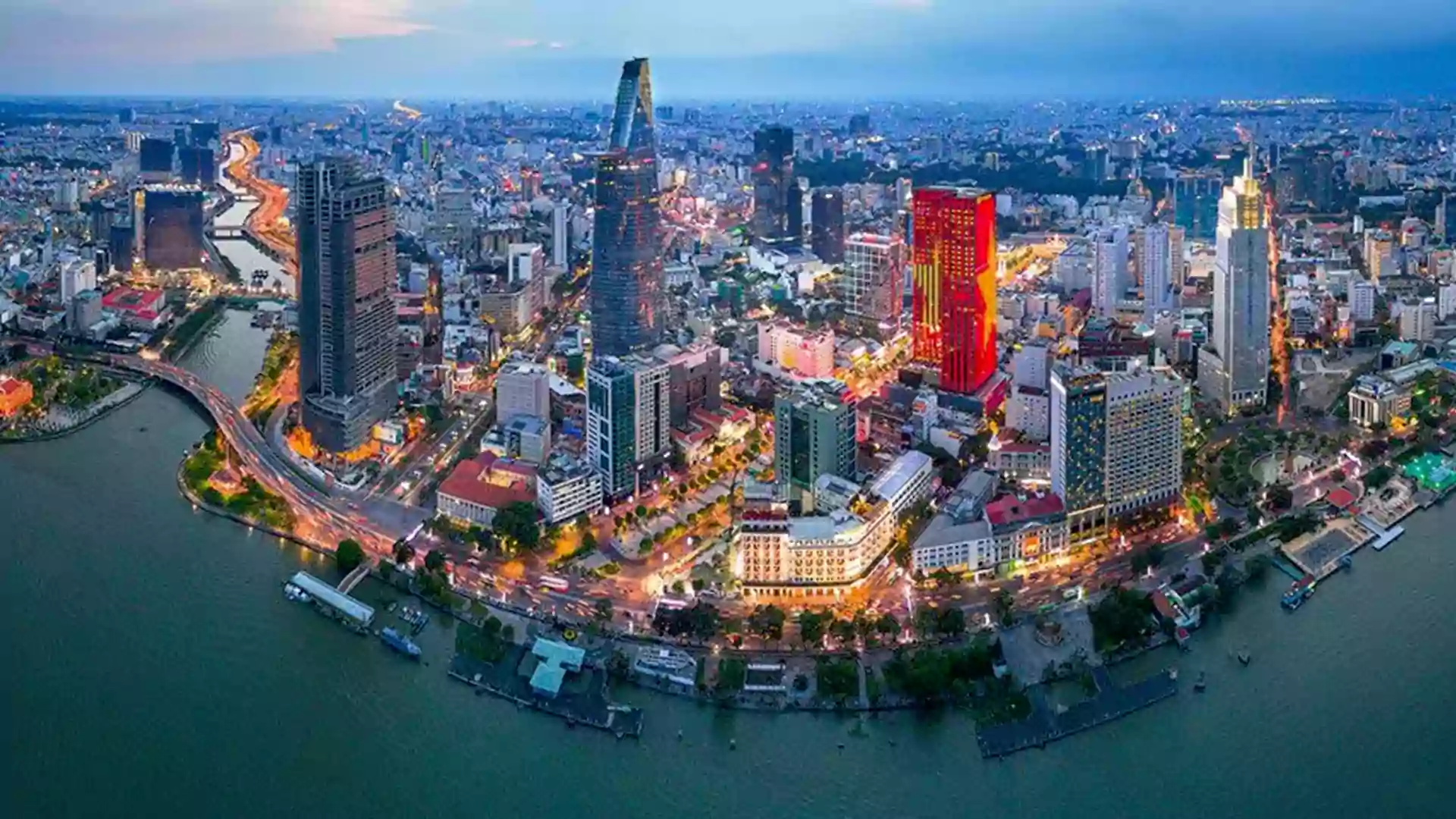 Pemandangan kota Ho Chi Minh City di malam hari dengan gedung pencakar langit dan lalu lintas yang ramai di sepanjang sungai