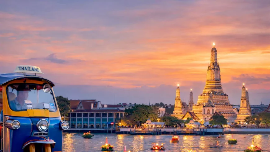 Pemandangan Wat Arun Bangkok saat matahari terbenam dengan tuk tuk di tepi Sungai Chao Phraya dan krathong terapung di air.