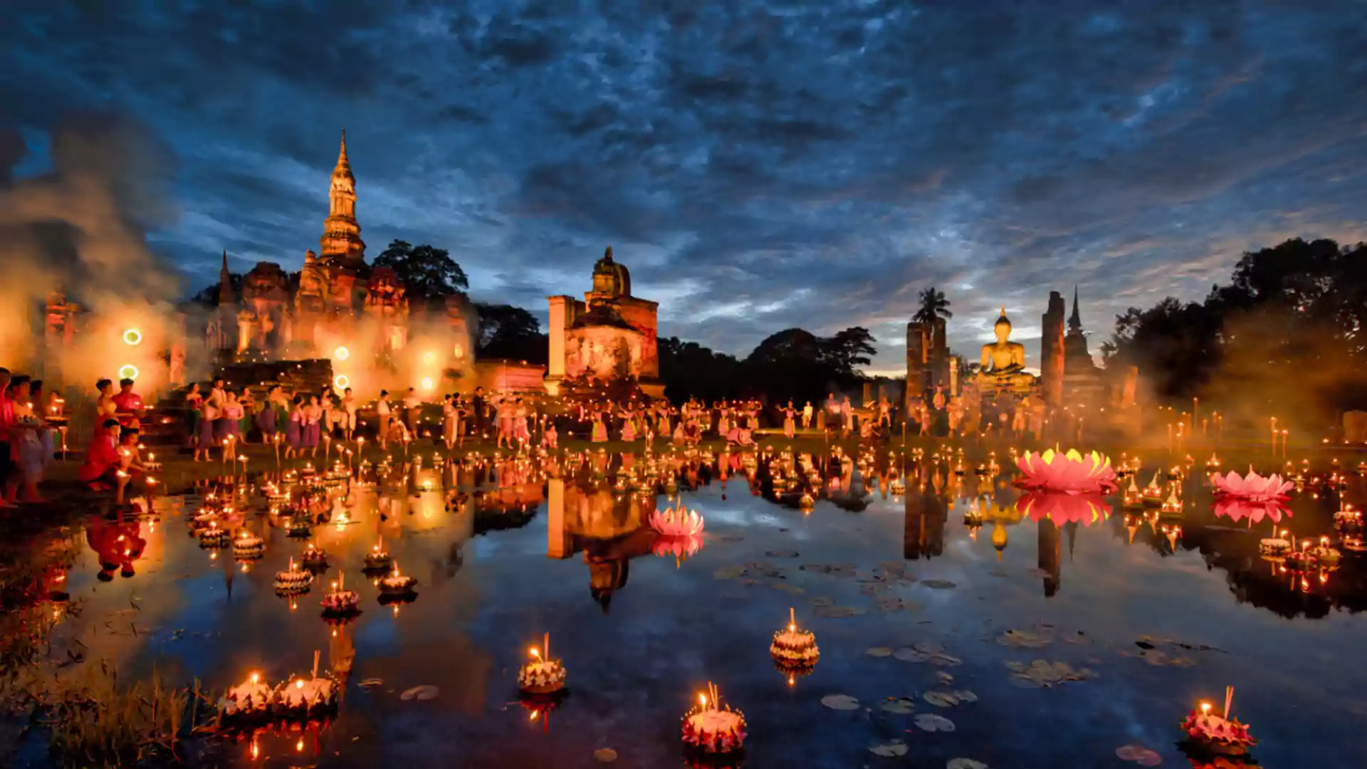 Festival Loy Krathong di Thailand dengan lampion dan krathong terapung di danau di depan kuil bersejarah pada malam hari.